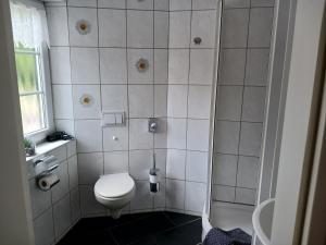 a white bathroom with a toilet and a shower at Hotel Forsthaus Glüsing in Schnakenbek