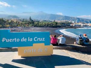 personas sentadas en la playa en Puerto de la Cruz en Estudio Ático Sol y Playa piscina en Puerto de la Cruz