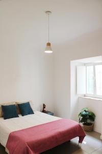 a white bedroom with a large bed with a red blanket at Casa das Nobres in Évora