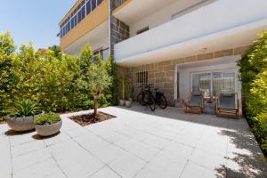 a courtyard of a building with two chairs and trees at The 98 Place Carcavelos in Carcavelos
