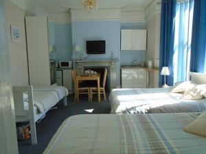 1 dormitorio con 2 camas y cocina con mesa en The Florian en Weymouth