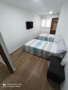 1 dormitorio con 2 camas y TV. en Apartamento vacacional, en Torrevieja
