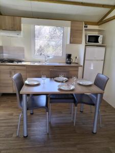 a kitchen with a wooden table and chairs and a kitchen with a refrigerator at Village de chalets et camping La Pierre de l'Aigle in La Bréole
