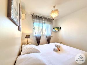 1 dormitorio con cama blanca y ventana en Perle des Camélias-T2 classé 3 étoiles sur Saint-Denis, en Saint-Denis