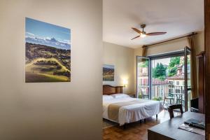 a bedroom with a bed and a large window at Hotel Il Grappolo D'Oro in Monforte dʼAlba