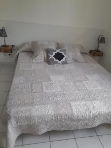 łóżko z szarą kołdrą i poduszkami w obiekcie Appartement T2 ocean location week-end 3 nuits hors saison avec terrasse et parking 200 m de la plage w mieście Moliets-et-Maa