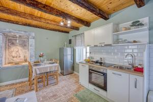 eine Küche mit weißen Schränken und einem Tisch mit einer Spüle in der Unterkunft Studio Jana with Balcony in Stranići kod Lovreča