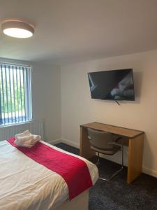 a bedroom with a bed and a desk and a television at City apartments college street in Hull