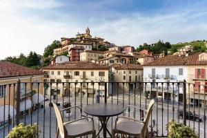 einen Balkon mit Stadtblick, einem Tisch und Stühlen in der Unterkunft Hotel Il Grappolo D'Oro in Monforte dʼAlba