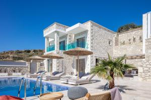 a villa with a swimming pool with chairs and umbrellas at Flower Village in Chania