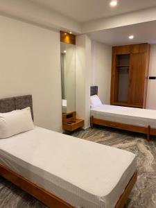 una camera d'albergo con due letti e uno specchio di Luxe Inn a Kannur