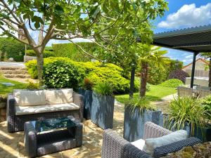 a patio with a couch and chairs and a table at La Maison de Manolie in Courcelles-Sapicourt