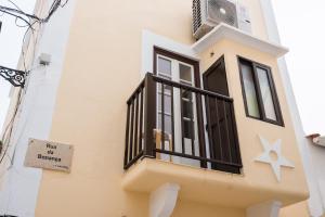 een gebouw met een balkon met een bord erop bij The Bird House in Nazaré