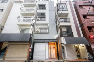 an apartment building with two garage doors on a street at NEW OPEN! Nearest JR Shinokubo and JR soubu line HIgashinakano, shinjuku 5 minute ginza 25 minute asakusa 35 minute in Tokyo