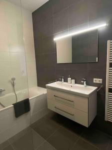 y baño con lavabo, espejo y bañera. en New and modern apartment in the city center, en Maastricht