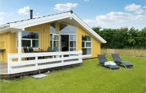 a yellow cottage with two chairs on the grass at Pet Friendly Home In Rudkbing With Sauna in Spodsbjerg