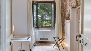 a room with a window and a table and a chair at MASSERIA TARSIA INCURIA 8&4, Emma Villas in Conversano
