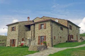a large stone house in a grassy field at Agriturismo D'ambiano in Arezzo