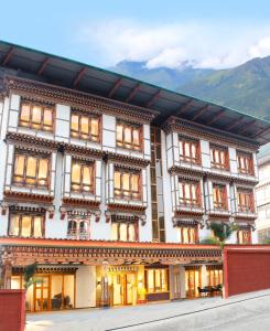 a large white building with windows and mountains in the background at Hotel Mayto in Thimphu