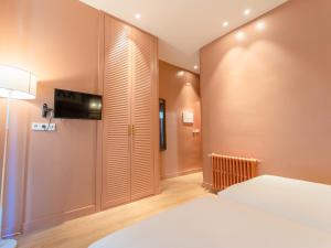 a bedroom with a bed and a flat screen tv at U-Sense Granada Centro in Granada