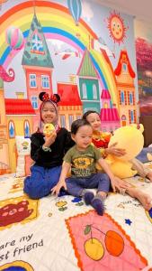 tres niños sentados en una cama en un dormitorio de Disney en Disney Suite II@Champs Elysees en Kampar