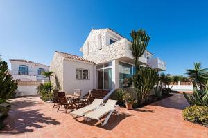 a house with a patio with chairs and a table at Casa Velero to 100mt from beach , optical fiber in La Oliva