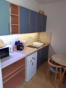 a small kitchen with blue cabinets and a table at SpaRelax Apartman Zalakaros in Zalakaros