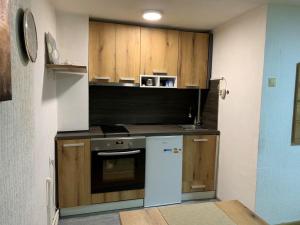 a kitchen with wooden cabinets and a white refrigerator at Apartman Kostadinovic in Pirot