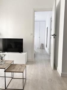a white living room with a flat screen tv at Smart Stay Córdoba in Córdoba