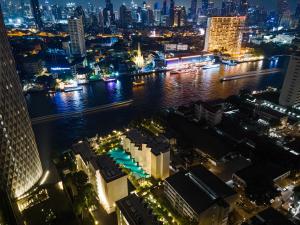 un profilo della città di notte con un fiume e edifici di The Quarter Chaophraya by UHG a Bangkok