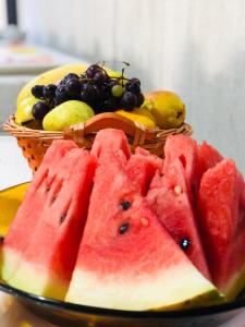 a basket of fruit on a table with a plate of watermelon at Posada Don Manuel in Paso de los Toros