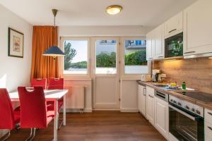 a kitchen with a table and red chairs and a table and a counter at Seehof Seehof 2 0 in Bansin