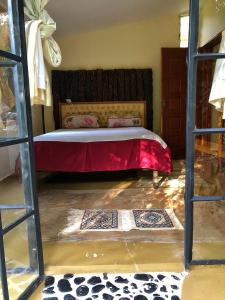 um quarto com uma cama com um cobertor vermelho em The Murana Chalet em Nanyuki