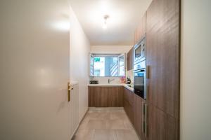a hallway with a kitchen with wooden cabinets and a door at Havre de paix - Appt avec terrasse in Courbevoie