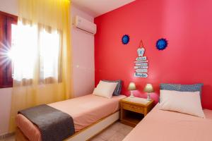 two beds in a room with a red wall at Entire vacation house near beach in Gournes