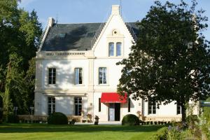 a large white house with a red awning at Le Manoir de Bellerive in Le Buisson de Cadouin