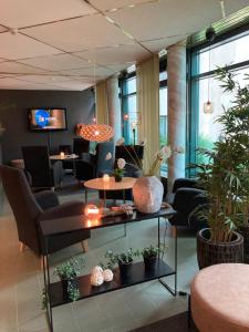 a lobby with chairs and tables and plants in a room at Hotell Björken in Umeå