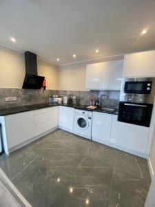 a kitchen with white cabinets and a washer and dryer at Jackson Holiday Apartments in Blackpool