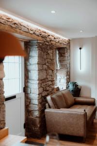 a couch in a living room with a stone wall at Brecon Cottage A Luxury Hikers Retreat in Brecon