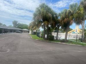 an empty parking lot with palm trees and a fence at Flamingo Inn in Sarasota