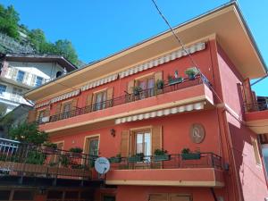 un edificio rojo con balcones y plantas. en La Randoulino, en Pomaretto