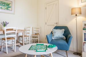 un salon avec une chaise bleue et une table dans l'établissement Giddy Cottage, à East Dean