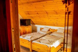 two beds in a room with a wooden ceiling at Nosztalgia Vendégház in Zalaegerszeg