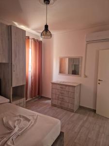 a bedroom with a bed and a dresser and a lamp at Suloti House Lungomare in Vlorë