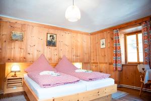 a bedroom with wooden walls and a bed with red and white sheets at Landhaus Geierwally in Elbigenalp