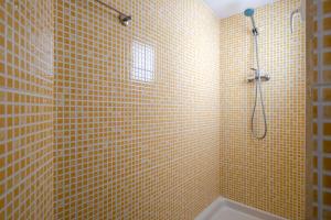 a yellow tiled bathroom with a shower and a tub at APARTMENT BEACH PICASSO in Sant Adria de Besos