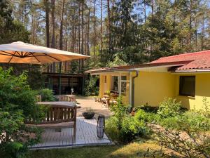 a yellow house with a bench and an umbrella at Ferienhaus im Wald in Borkwalde