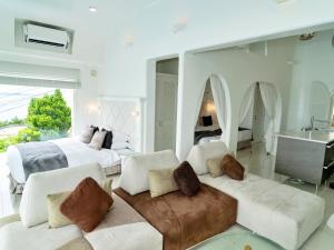 a white bedroom with a bed and a couch at Yuki Suite Kourijima in Nakijin