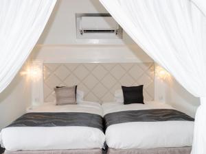 今帰仁村にあるYuki Suite Kourijimaの白いカーテンが備わる客室のベッド2台