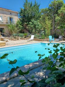 a swimming pool in a yard with two chairs at Shanti Home in La Tour-sur-Orb